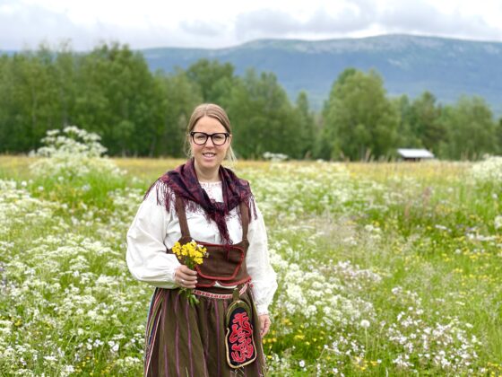 Midsommar i Vemdalen. Flicka på en äng full av blomster iklädd Vemdalsdräkten.