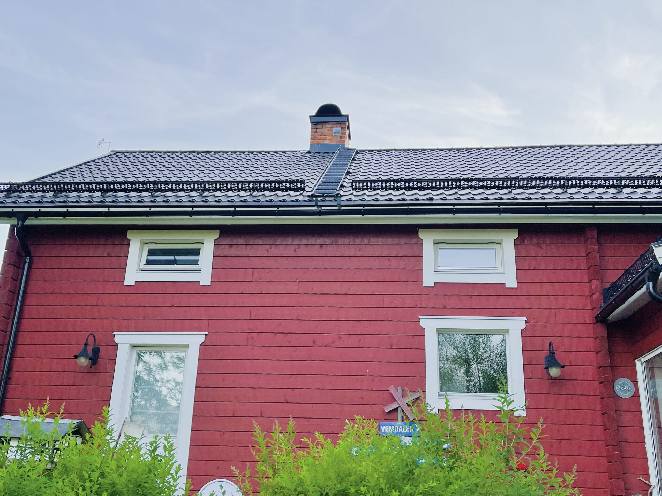 Vi kom hem till huset fullt av bin. Bilden visar ett rött hus med en skorsten där en bisvärm försökte bygga nytt bo.