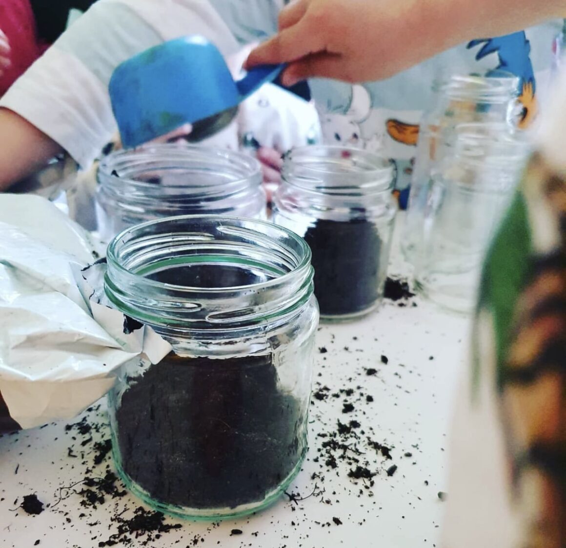 Odlingsdags hos Vemdalens förskola. Barnen öser jord i glasburkar.